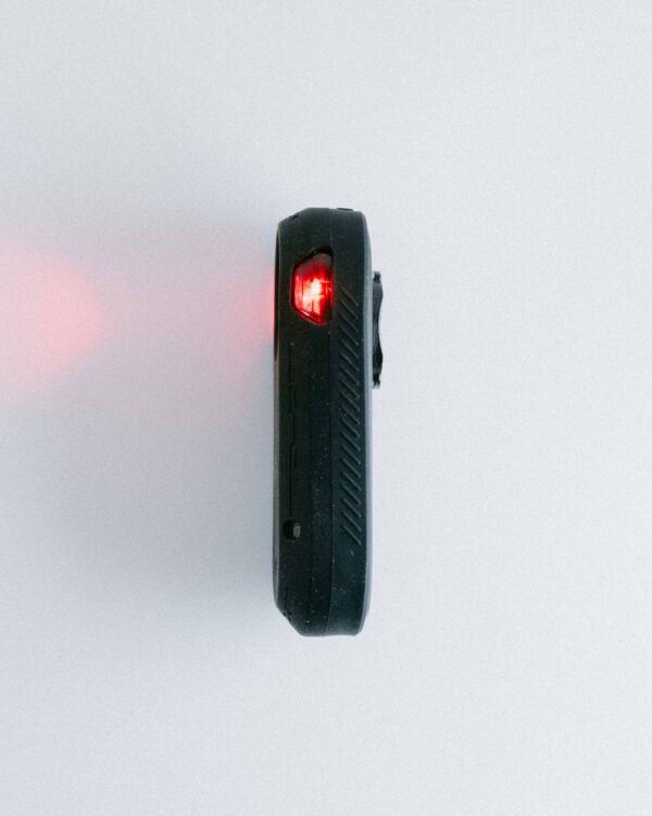 Side view of the Garmin Varia rear light with a black silicone cover and activated lighting.