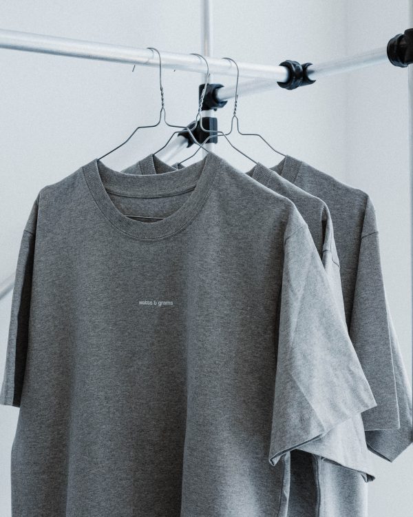 Gray watts and grams logo t-shirt unisex on hangers on a clothes rail.